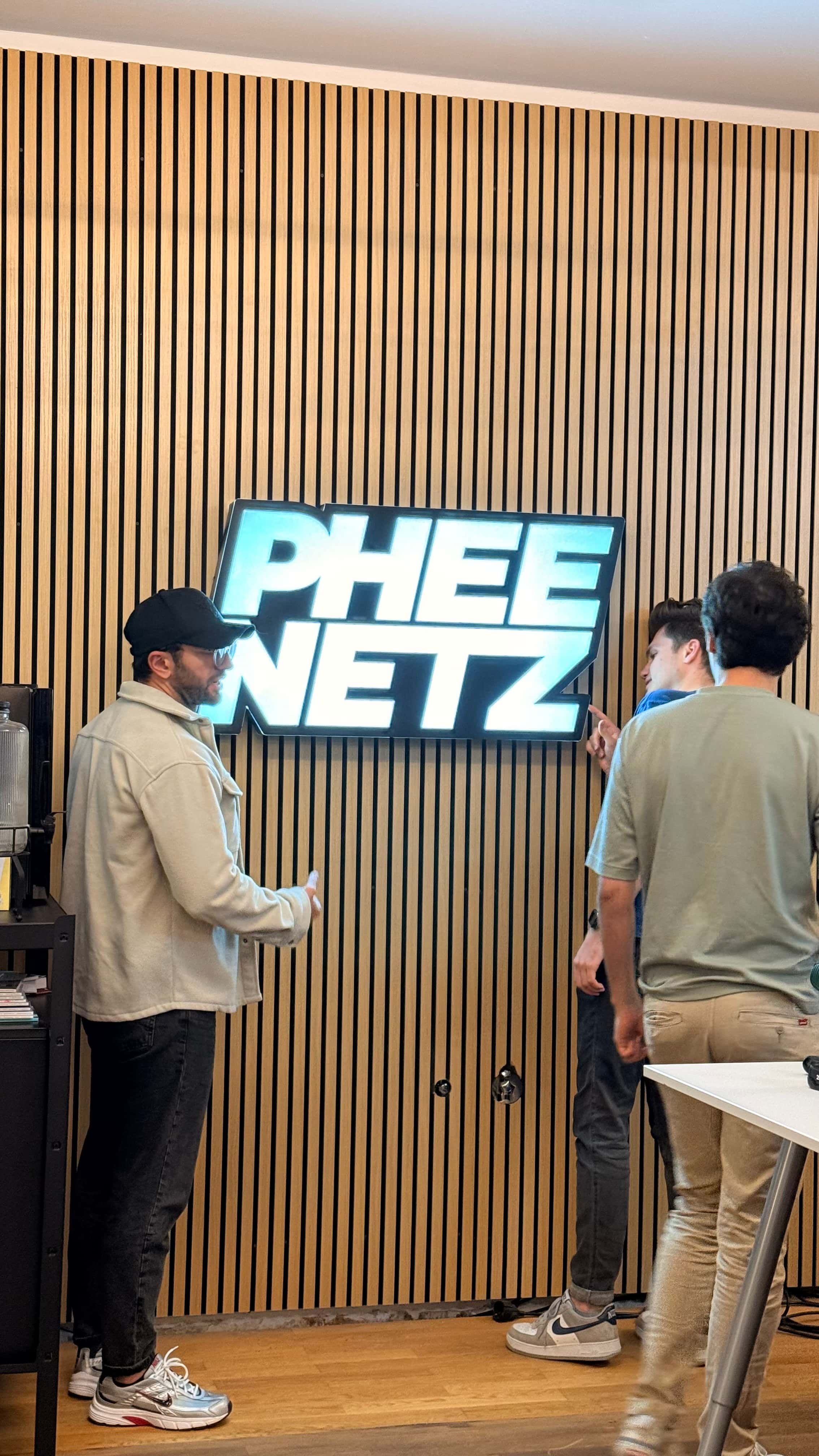 PHEENETZ Mitarbeiter stehen um ein PHEENETZ Schild